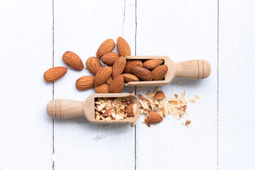 Almonds crushed into pieces and  almond in wooden spoon on a white background,Close up top view