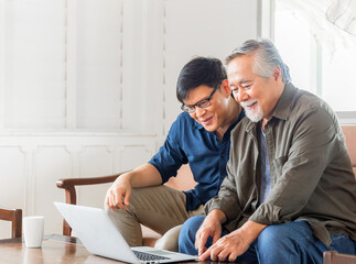 Happiness senior asian father and adult son using laptop talking on video call in living room