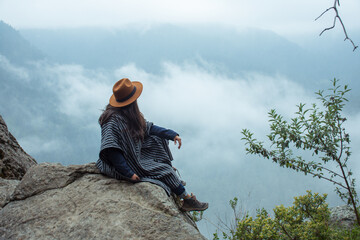 Mujer sentada en una roca en las alturas