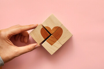 Heart sign on wooden cubes. A person collects a picture of a heart