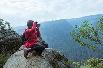 Chica sentada tomando foto en una montaña