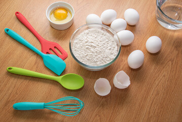 Baking Cooking Ingredients Flour Eggs colorful Kitchen utensils On Bright woody Background. Top View Copy Space. Cookies Pie Or Cake Recipe.