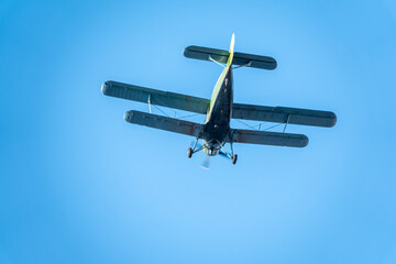 Retro green biplane plane in the blue sky