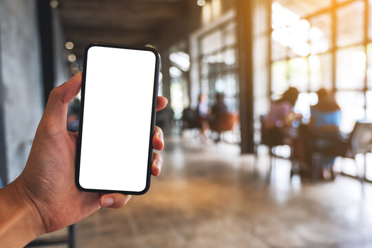 Mockup image of a man holding black mobile phone with blank white screen in cafe