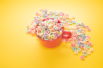 Bowl of Cereal, Colorful cereal in a bright red bowl on wood, cereal loops on a yellow background. Quick breakfast or snack, flat lay.