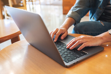 Closeup image of a woman working and typing on laptop computer keyboard on the table
