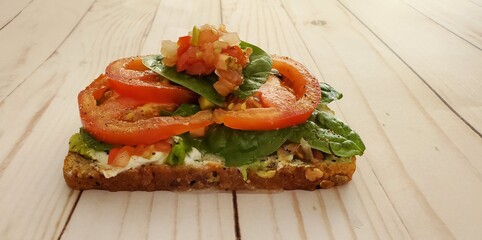 Avocado toast with yogurt, a small squeeze of fresh lemon juice, spinach leaves, sliced tomatoes and fresh salsa
