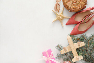 Composition with Christmas decor, airplane and female accessories on white background
