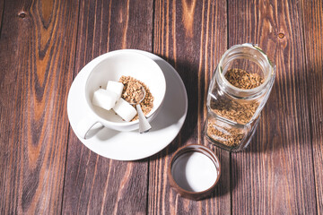 freeze-dried coffee, a Cup filled with freeze-dried coffee and a piece of refined sugar at the bottom of the Cup, on a wooden table