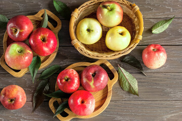 apples in wooden bowls and basket on the table close-up. red apples on a wooden background.
