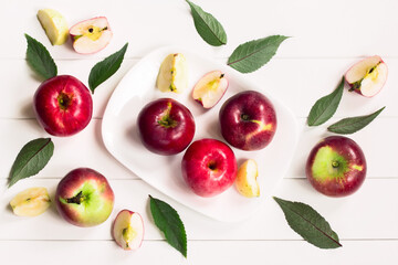 Apple slices, apples, green leaves on a white background top view. background with apples in a white plate on a white table.