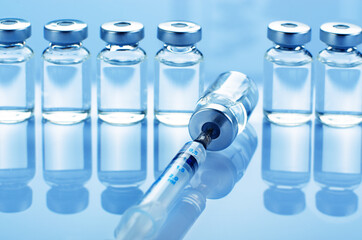 Vial with liquid drug as vaccine dose flu shot along with syringe for injection treatment on...