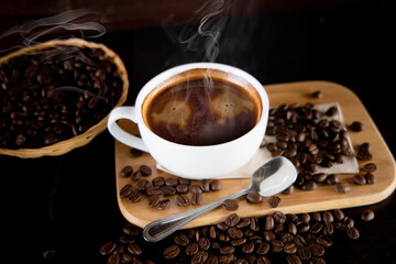 coffee cup with smoke, a spoon and coffee beans placed on a small basket beside it.