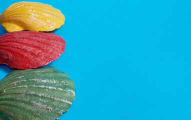 Marine layout. Three seashells painted red, yellow, and green on a blue background.