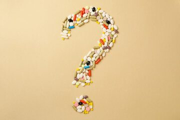 Question mark made of pills on beige background