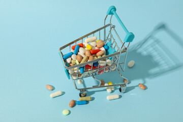 Shop cart with different pills on blue background