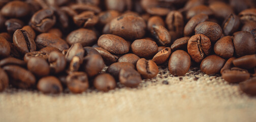 Roasted coffee beans on burlap. Background for coffee shops and store websites. Selective focus and blur