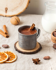 Hot chocolate in a metal mug with a cinnamon stick on the tablecloth. Copy space