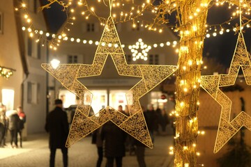  Christmas and New Year in Europe. Christmas holidays in Germany.Golden decorative star and shining garlands on blurred street background. Street Christmas decor.Christmas time.Winter 