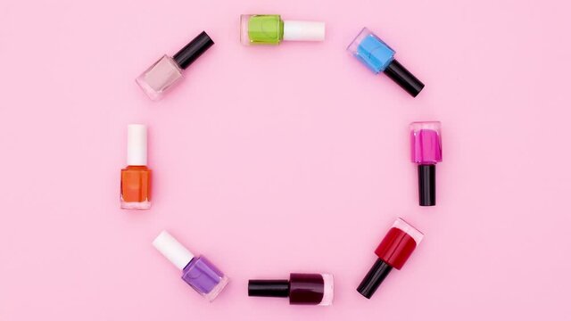 Colorful bottles of nail polishes move in circle . Stop motion 