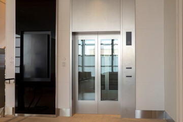 Modern elevator with metallic cabin with glass door