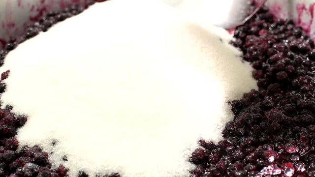 Falling asleep and stirring sugar in blueberry jam, close-up, background