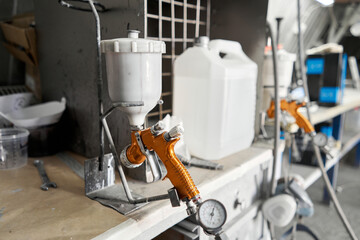 Image of Spray gun. Worker painting parts of the car in special painting chamber, wearing costume...