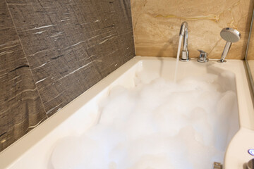 Interior of marble bathroom with bathtub full of foam bath