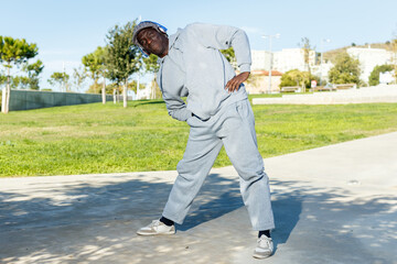Obraz premium Portrait of athletic african american male performs warm-up exercises in park
