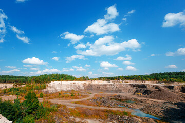 Excavator and heavy mining dump trucks in a limestone quarry