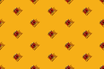 Yellow Christmas background. Drum seamless pattern. Winter holidays celebration decor. Festive adornment. Golden red vintage toy music instrument symmetrical arrangement isolated on bright orange.