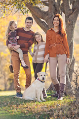 Family resting in nature in autumn. Beautiful woman with a man have fun playing with children. High quality photo.