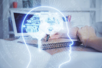 Multi exposure of writing hand on background with brain hologram. Concept of self learning.