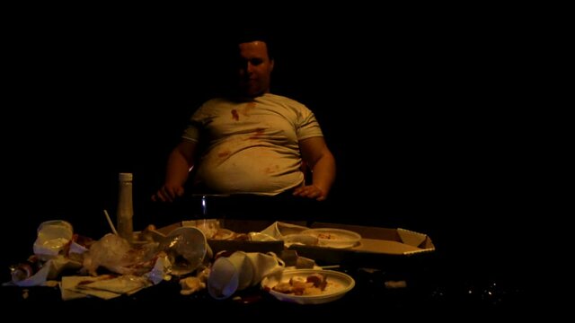 Fat man eating junk food burgers and hot dogs and watching TV, slow mo, Overweight