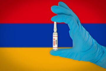 New coronavirus vaccine with the flag of Armenia in the background. Armenia medical research and vaccine development center. Doctor holding coronavirus vaccine in his hand.