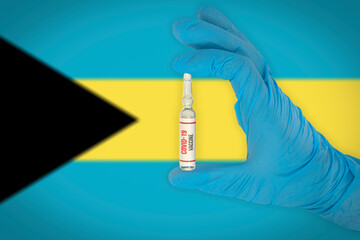 New coronavirus vaccine with the flag of Bahamas in the background. Bahamas medical research and vaccine development center. Doctor holding coronavirus vaccine in his hand.