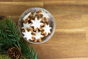 Obraz na płótnie Canvas A cup with christmas biscuits on a wooden table and with fir branches, top view