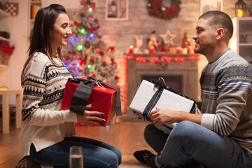 Happy girlfriend and boyfriend on christmas day giving each other gifts.