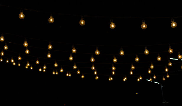 a row of light bulbs hanging on the street at night