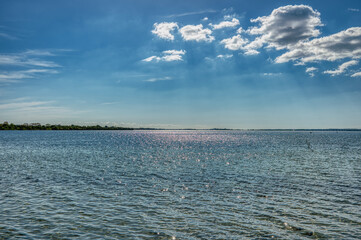 Blue sky with sun rays peeping through the clouds reflecting on a calm Baltic Sea convey eternal freedom and motivational concept with sublime ecstatic, peace of mind and happiness - Praesto, Denmark