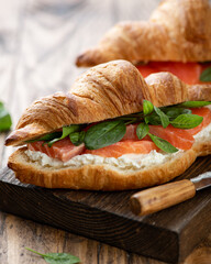 croissant with salmon, spinach and cream cheese on a wooden board, selective focus, close-up