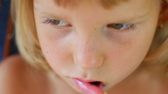 The child shows his first staggering tooth. Finger loosens baby's tooth.