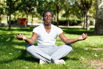 Fototapeta premium Portrait of athletic african american in headphones sitting before training in park