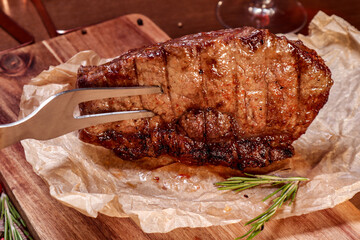 Marbled veal fried on charcoal with vegetables and spices on a wooden board. European cuisine.