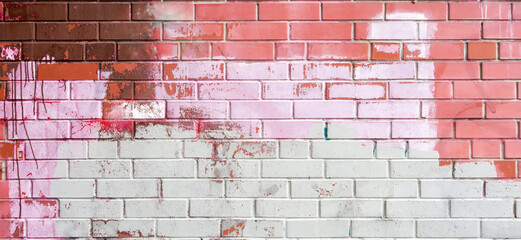 Texture of old colored bricks. Close-up of a red-and-white brick wall with old peeling paint. Ancient brick wall background for graffiti. Horizontal background with free space for text