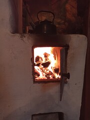 Old traditional russian stone stove with kettle and firewood. Peasant's life village. Wood heating of izba, hut. Baking oven. Oven for cooking.