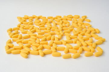 pharmacy industry concept of handful of yellow tablets lying on white surface