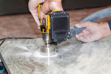handyman cut round holes for electrical outlets in marble countertop for the kitchen using hand...