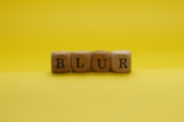 Blur Word Written In Wooden Cube With Yellow Background and Blur concept