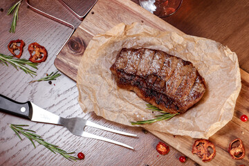 Marbled veal fried on charcoal with vegetables and spices on a wooden board. European cuisine.